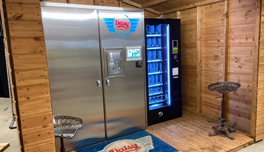 A Milkshake vending machine in a wooden shed equipped with JB Syrups.