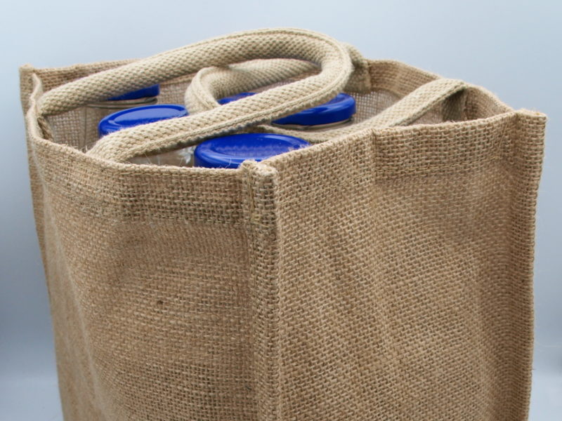 A Handy 6 Bottle Carrier With Divider - Jute filled with blue bottles of JB Syrups.
